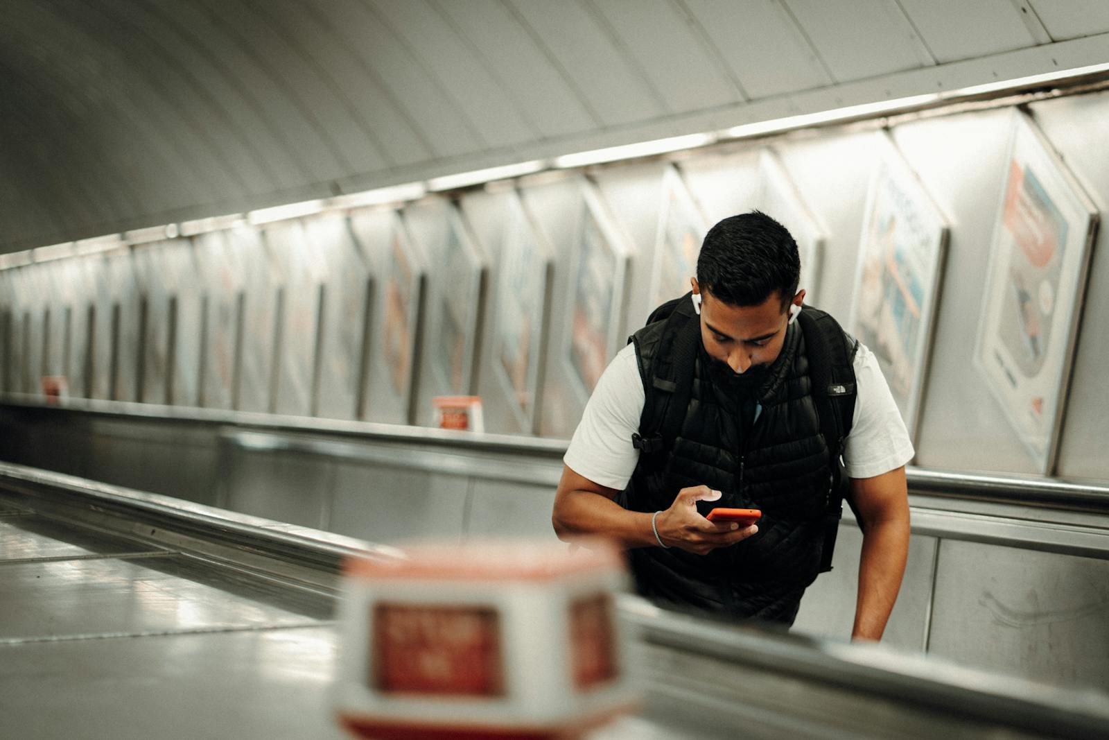 Traveler checking a phone while riding an escalator